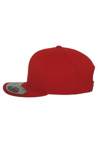 Rød baseballkasket med flad skygge, lavet af stof, med ventilationshuller og et dekorativt mærke på undersiden af skyggen.