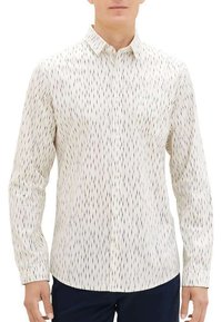 Chemise blanche à manches longues avec des lignes ondulées verticales bleu marine et noires. Dotée d'un col et d'une poche poitrine.