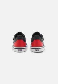 Sneaker Converse nere e rosse con suole bianche, caratterizzate da una tomaia in sintetico liscio e un logo sul tallone, che mostrano un design a collo basso.