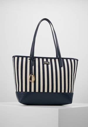 Marineblauwe en witte gestreepte draagtas met leren bodem en handvatten, gouden gespdetail, en een klein logoplaatje aan de voorkant.