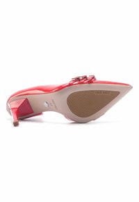 Red patent leather high heel shoe with a pointed toe, embellished with two wide straps and a thin heel. Rubber sole with patterned tread.