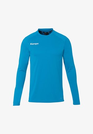 T-shirt de sport bleu à manches longues avec col rond, présentant un logo blanc "Kempa" sur la partie supérieure gauche de la poitrine.