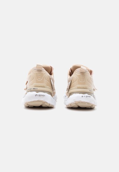 Μπεζ αθλητικά παπούτσια DSQUARED2 με λευκές χοντρές σόλες, πίσω όψη που δείχνει το όνομα της μάρκας και χειρόγραφες λέξεις στα άκρα της σόλας.