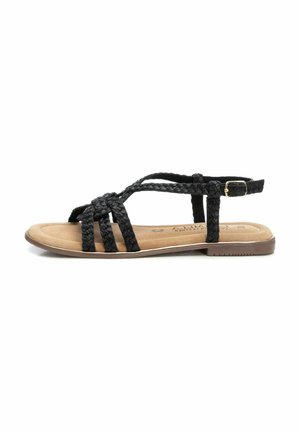 Sandalias planas trenzadas negras con una correa para el tobillo ajustable y una plantilla acolchada en color marrón, que presentan una suela de goma marrón de perfil bajo.