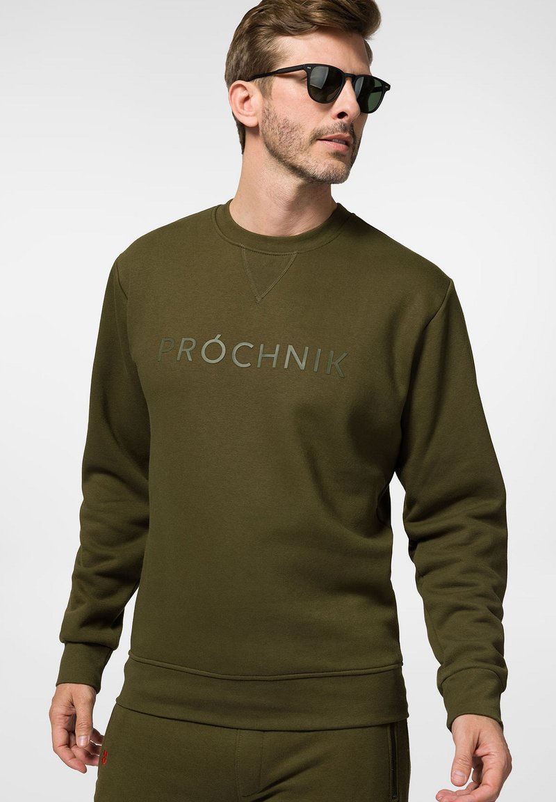 Oliwkowy sweatshirt wykonany z mieszanki bawełny, z długimi rękawami, okrągłym dekoltem i wypukłym napisem logo na środku. Gładka faktura.