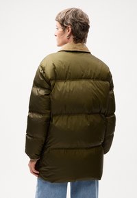 Jachetă puffer verde măsliniu cu guler moale bej, textură matlasată și croială lejeră. Prezintă cusături orizontale și o siluetă relaxată.