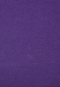 Tejido de punto en un rico tono púrpura, que presenta una superficie texturizada con un patrón uniforme de finas puntadas. Material suave y flexible.