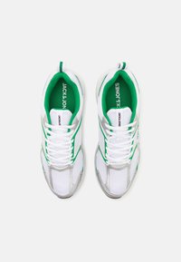 Hvide mesh sneakers med grønne og sølvfarvede accenter. Har rund tå, snørelukning, polstret krave og teksturerede sidepaneler.