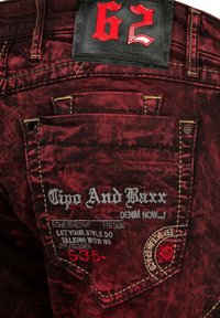 Diep rode denim jeans met een reliëf zwart leren label met het nummer 62. Decoratieve stiksels en geborduurde branding op de achterzak.