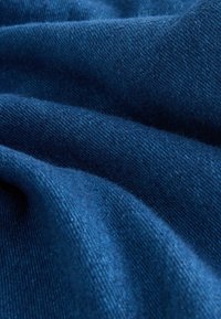 Donkerblauwe stof met een zachte, textuurrijke oppervlakte. Het materiaal heeft een subtiele glans en vertoont een fijn twillpatroon, wat de visuele diepte versterkt.