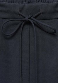 Zwarte trekkoord tailleband met een strikdetail en een gladde stoftextuur. Bevat subtiele horizontale stiksels langs de taille en voorkant.