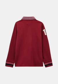 Polo à manches longues de couleur bordeaux avec un col gris clair. Présente un numéro "1" blanc sur la manche droite et des accents multicolores aux poignets.