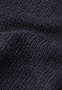 Texturerat mörkblått tyg med en bumpig, upphöjd mönstring som visar ojämna ytor och djupvariationer.