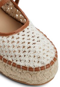 Offene Espadrilles mit einem weißen gehäkelten Obermaterial und einem braunen Lederbesatz. Verfügt über eine geflochtene Jutesohle und eine strukturierte Stoffoberfläche.
