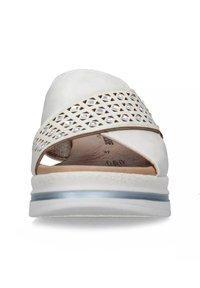 Scarpa bianca slip-on con design a fascia incrociata, caratterizzata da motivi a intaglio, una parte superiore texturizzata e una suola di un blu chiaro a contrasto.