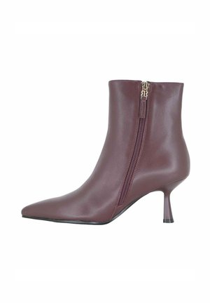Stivaletto alla caviglia in pelle bordeaux con punta affilata, tacco a stiletto sottile, chiusura con zip laterale e texture liscia.