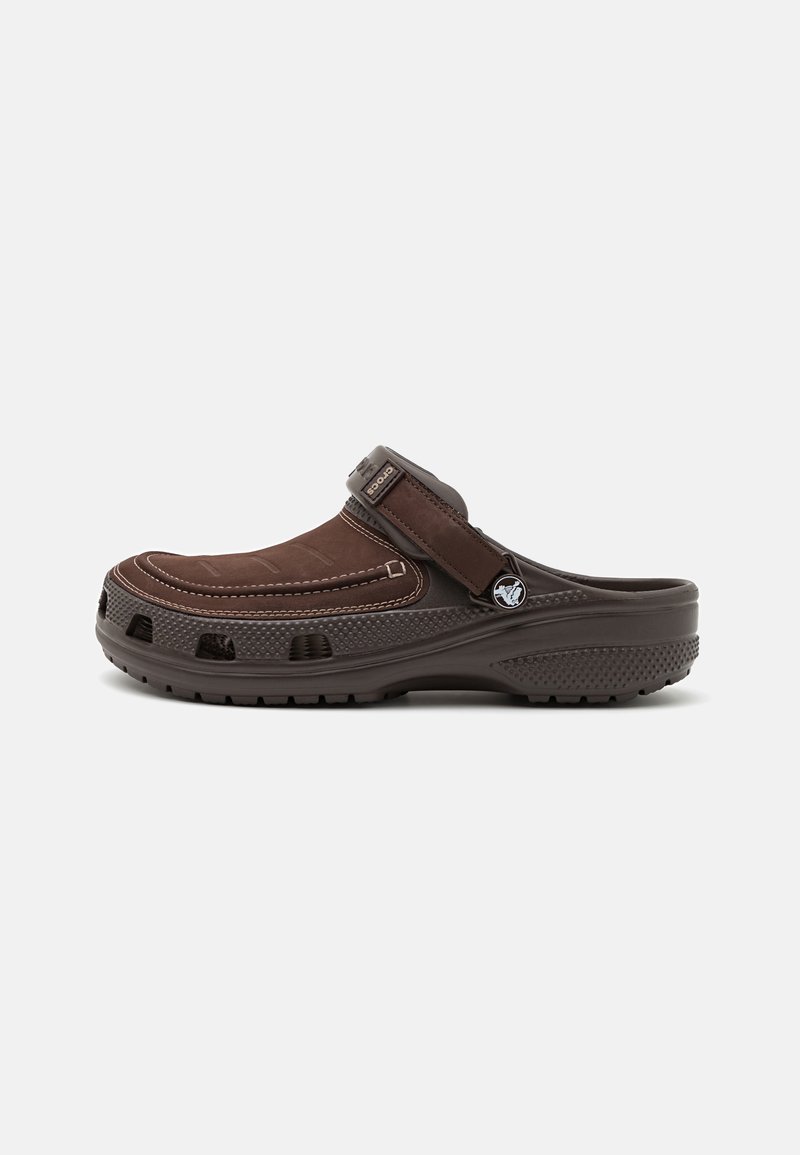 Sabot en cuir marron avec un dessus à texture douce, sangle ajustable et design perforé pour la ventilation. Semelle épaisse en caoutchouc pour l'adhérence.