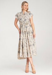 Blumengemustertes, beige Maxi-Kleid mit kurzen Ärmeln, gerafftem Bund und Bindeband. Merkmale sind der fließende, texturierte Stoff und das geschichtete Design.