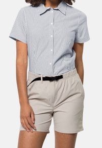 Kortärmad skjorta med krage i blå och vita ränder, som matchas med ljusbeige shorts med elastisk midja och svart bälte.