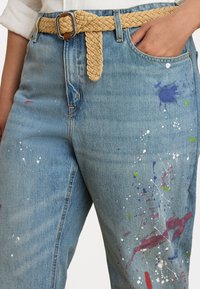 Denim jeans med høy midje, utsmykket med fargerike malingsprut, et flettet beige belte og en avslappet silhuett.
