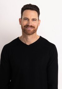 Maglione nero a maniche lunghe con scollo a V, texture lavorata a maglia, design aderente, indossato da un uomo su uno sfondo chiaro, con un leggero dettaglio sullo scollo.