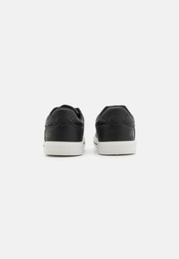 Mustad nahast sneakerid siledaga tekstuuriga, pehme krae ja kontrastse valge kummitald. Minimalistlik disain logoga kanna peal.