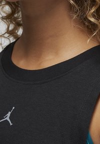 Black sleeveless shirt with a round neckline, featuring a prominent white Jordan logo on the chest. Cotton blend with smooth texture.