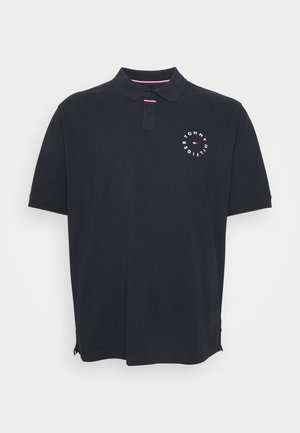 Sort polo med korte ærmer, to knapper foran og et rundt Tommy Hilfiger-logo på venstre bryst.