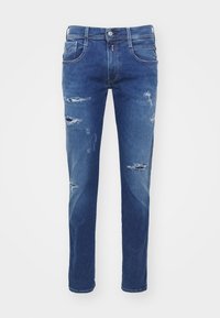 Blå denimjeans med slim fit, med flera slitna områden och trasiga lappar. Knappgylf och femfickorsdesign.