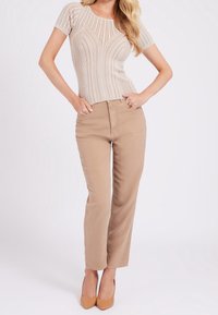 Top de punto acanalado beige con mangas cortas, combinado con pantalones rectos de color marrón claro y tacones altos en color tostado. Diseño sencillo y textura suave.