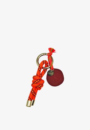 Porte-clés en métal avec une corde rouge-orange nouée et une étiquette rouge avec un symbole de paix, attachée par un cordon court multicolore avec un charme en métal.