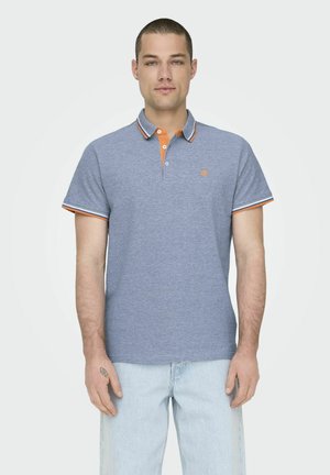 Graues Poloshirt mit orangefarbenem Kragen und gestreiften Ärmelakzenten, aus Baumwolle gefertigt, mit kleinem Logo auf der Brust. Getragen mit hellblauen Jeans.