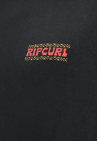 T-shirt noir avec un logo "RIPCURL" en rouge vif et des accents jaunes, entouré d'un motif géométrique de style tribal.