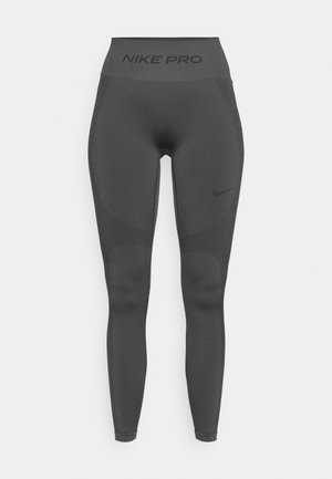 Nike Pro legíny v tmavošedej tkanine. Vysoký pás s textom "NIKE PRO". Hladká textúra so subtílnymi vzormi a detailmi značky.