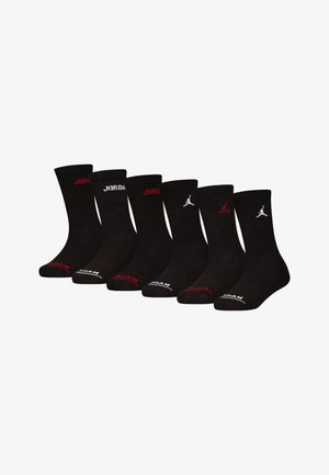 Sei coppie di calzini neri in cotone. Le caratteristiche includono una texture a coste, testo "JORDAN" in rosso e bianco, e logo Jumpman su alcune paia.