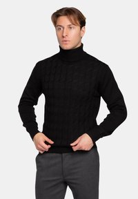 Maglione nero a collo alto con un motivo testurizzato, polsini e orlo a costine. Realizzato in tessuto lavorato a maglia, presenta un design aderente.