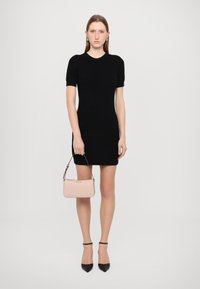 Black ribbed short-sleeve dress, fitted design. Light pink handbag with a strap, paired with black pointed heels and ankle straps.