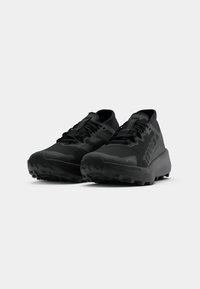 Schwarze Sportschuhe mit strukturiertem Obermaterial, robuster Laufsohle und prominentem Logo. Verfügt über ein Schnürdesign und eine gepolsterte Sohle für besseren Halt.