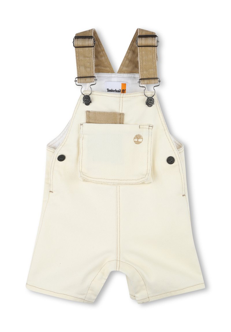 Salopette courte en velours côtelé beige clair avec bretelles ajustables, poche avant et logo Timberland. Le tissu est d'une couleur crème claire avec des détails de couture.