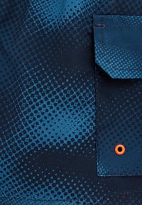 Mėlynas tekstilės audinys, turintis gradientą apskritų taškų raštais, su išsiskiriančia oranžine anga ir šviesiai mėlyna kišene. Lygus paviršius.