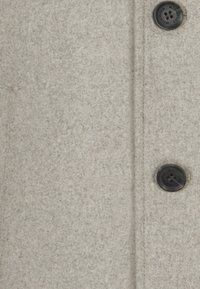 Helle graue Wolljacke mit weicher Textur, die eine vertikale Naht und ein schwarzes Kunststoffknopf-Detail aufweist.