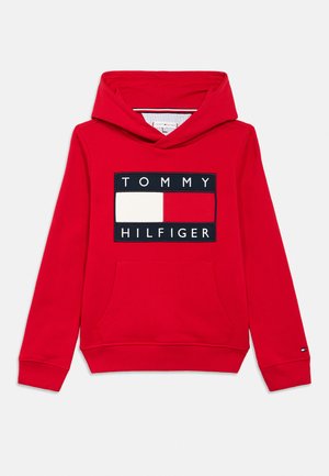 Piros kapucnis pulóver első zsebbel és a Tommy Hilfiger logó folt fehér, piros és tengerészkék színekben, felirattal a mellkason.