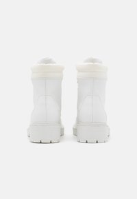 Et par hvide ankelstøvler med tykke såler og polstrede kraver, vist fra bagsiden på en ensfarvet hvid baggrund.