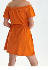 Oranžové šaty s odhalenými rameny, krátkými rukávy, přiléhavým pasem a rozevlátou sukní. Vyrobené z lehkého, hladkého textilu s jemným leskem.