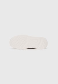 Shoe sole in white rubber with patterned tread, featuring embossed logo. The design includes curved grooves and a smooth finish.