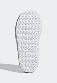 White sneaker sole with a textured pattern of small stars and diamonds. Edges are grey, showing a smooth transition to a light-colored upper.