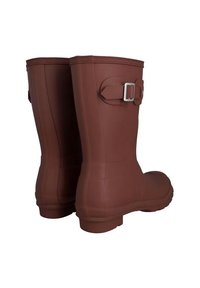 Botas de goma marrones, impermeables, con una textura suave, acabado semimate y detalles de hebilla ajustable en el lateral. Punta redonda y suela plana.