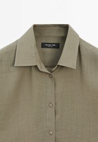 Lichtgroen linnen shirt met een klassieke kraag, knoopsluiting aan de voorkant en een gestructureerde afwerking. Label leest "Massimo Dutti."