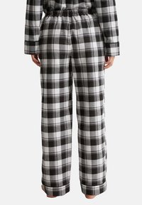 Schwarz-weiß karierten Flanell-Pyjama-Hosen mit einem elastischen Bund, geradem Bein und umgeschlagenen Säumen. Weicher Stoff und entspannte Passform.