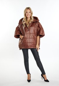 Bruine puffer poncho met een grote capuchon, rits aan de voorkant en zijzakken. Glanzende afwerking, korte wijde mouwen en verstelbaar hem detail.